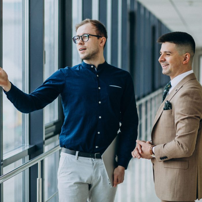 Two male colleagues at the office,standing with laptop Two male colleagues at the office,standing with laptop